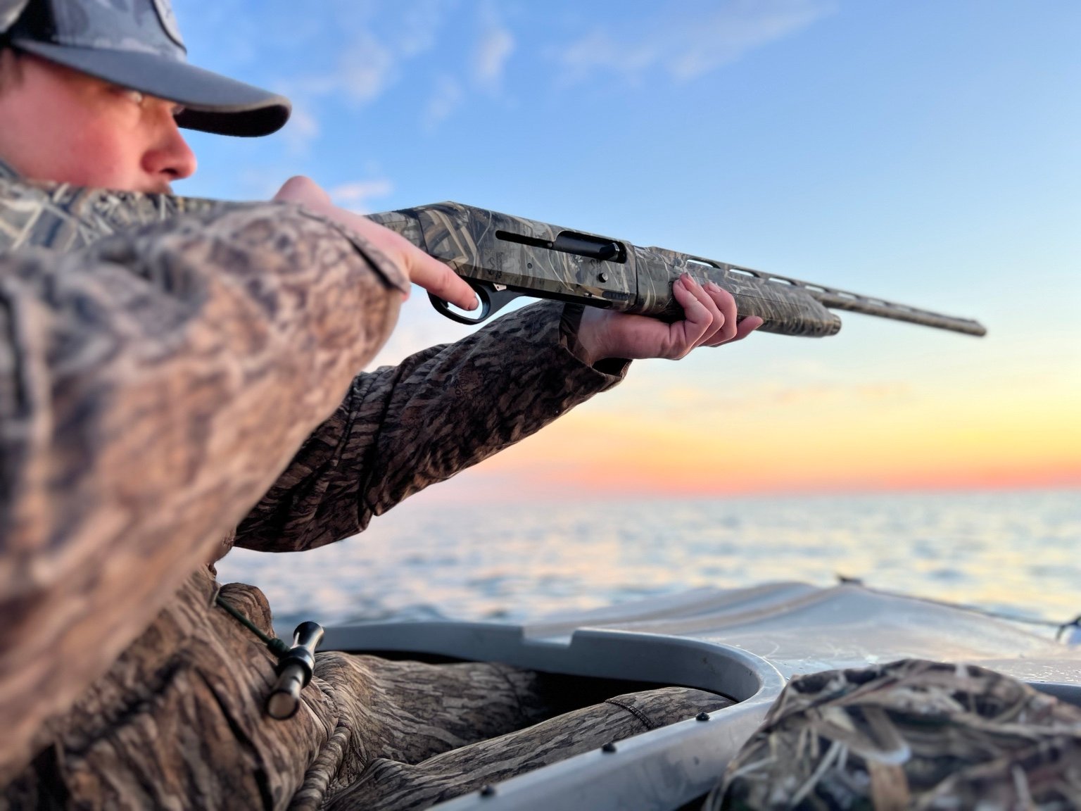 Duck hunter in a boat at sunrise